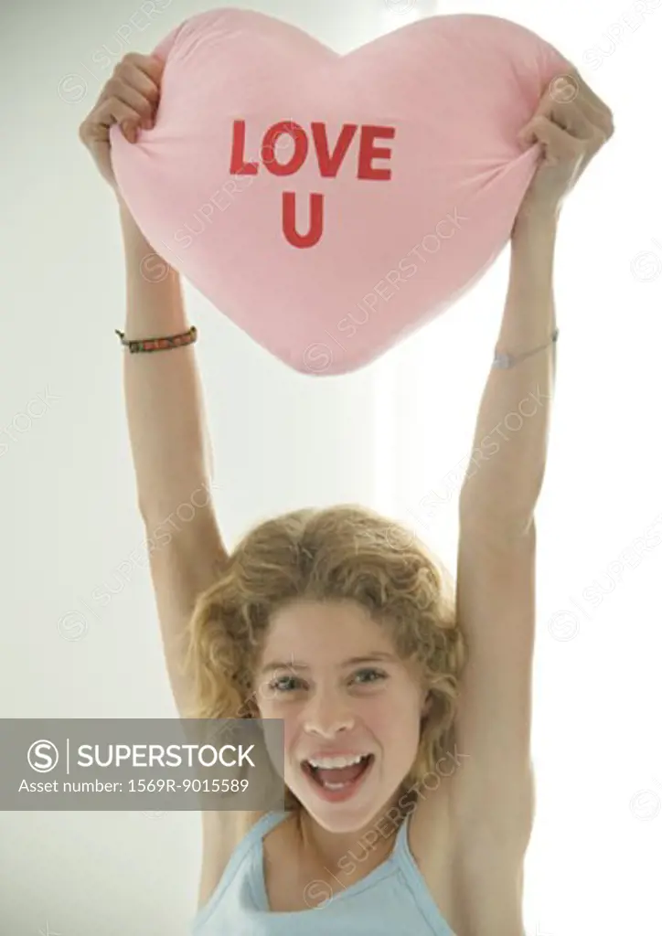 Preteen girl holding up heart shaped pillow