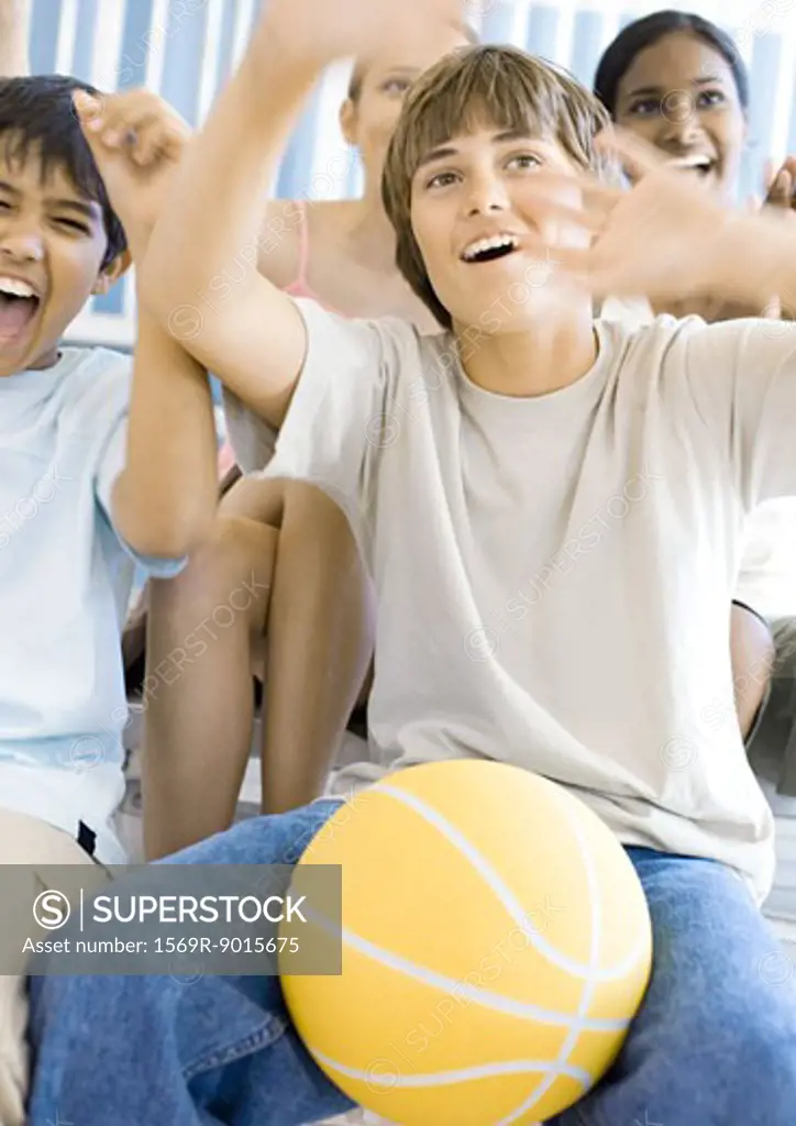 Group of high school students sitting with basketball, cheering