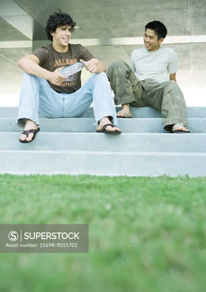 Two male college students sitting on steps together