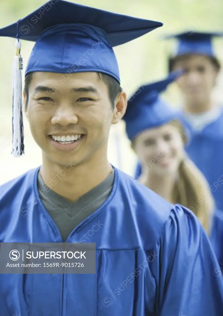 Graduates standing in line, focus on young man in foreground