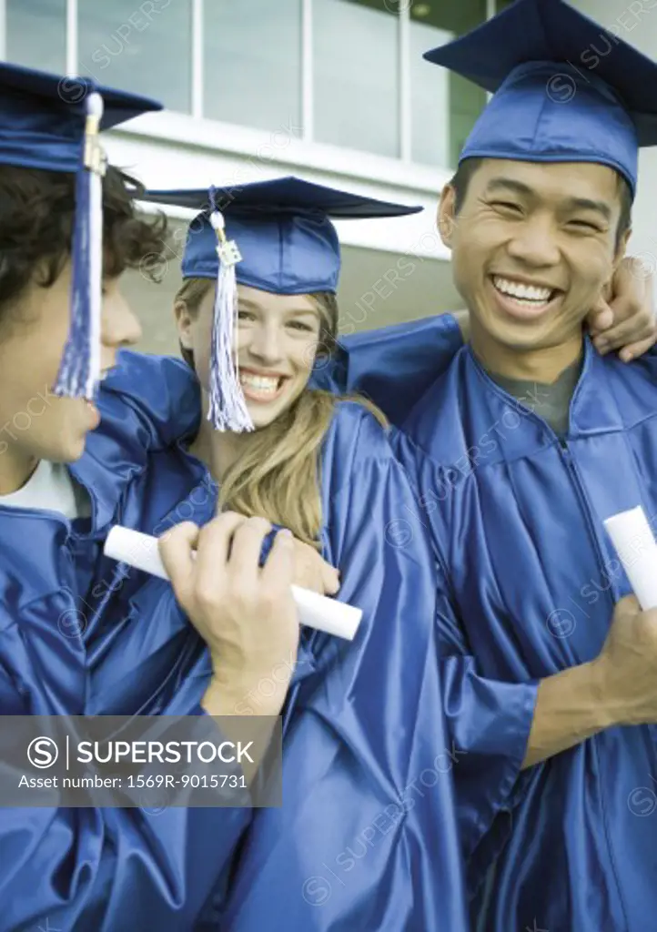 Graduates with diplomas, laughing