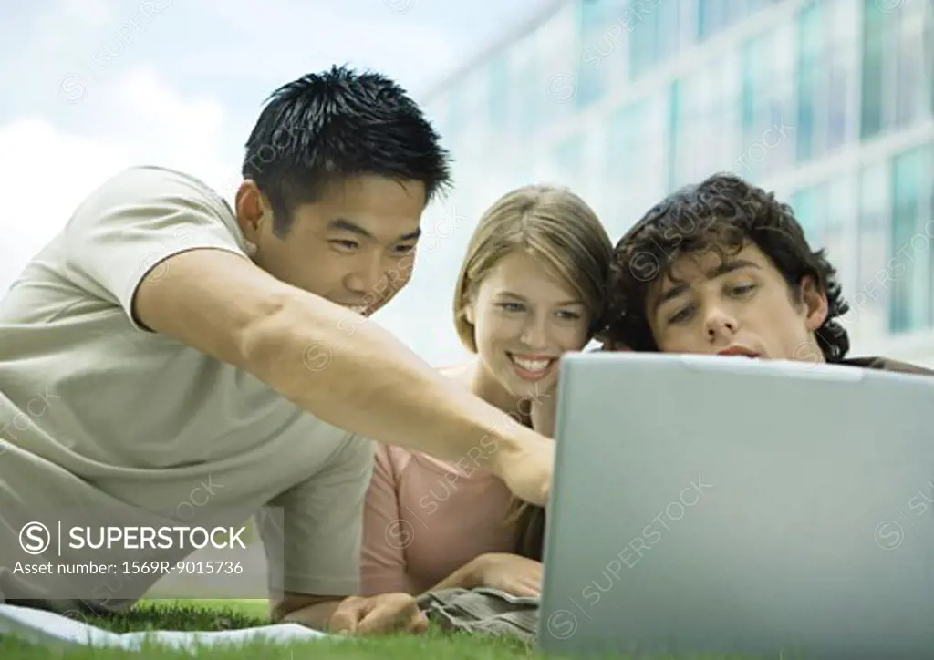 Three college students using laptop outdoors