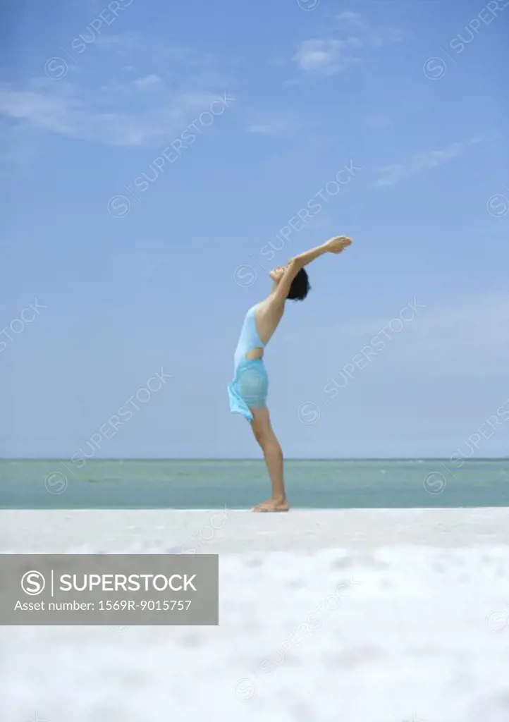 Woman performing sun salutation on beach