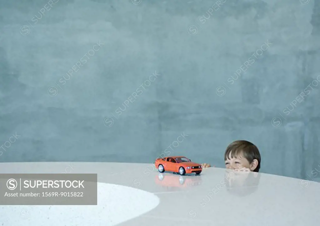 Boy peeking at toy sports car