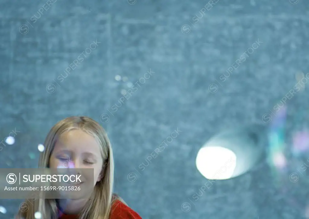 Girl closing eyes as bubbles float in the air