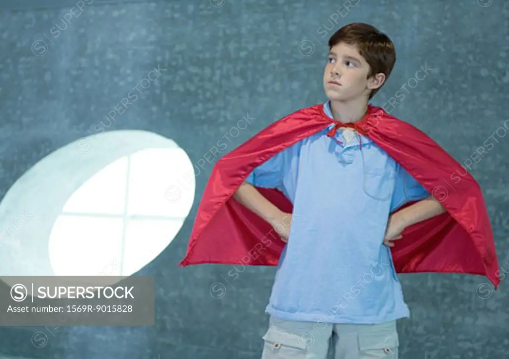 Boy wearing red cape, hands on hips