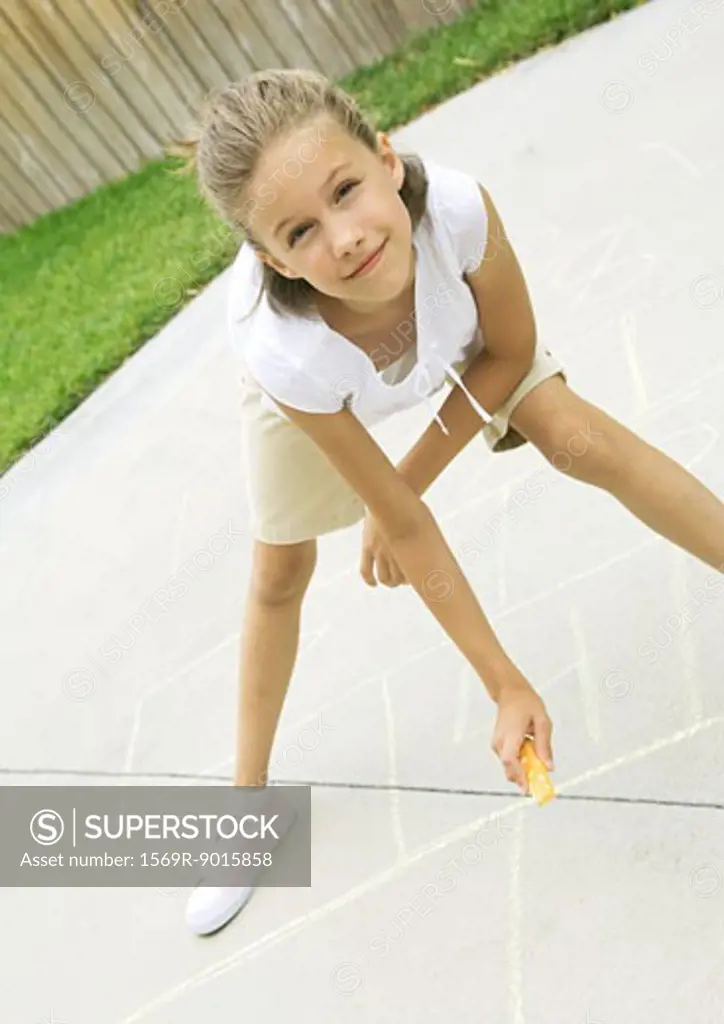 Girls drawing hopscotch squares on concrete