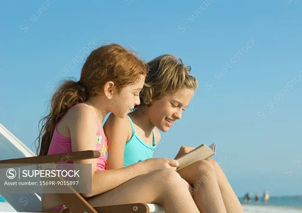 Two girls reading on beach