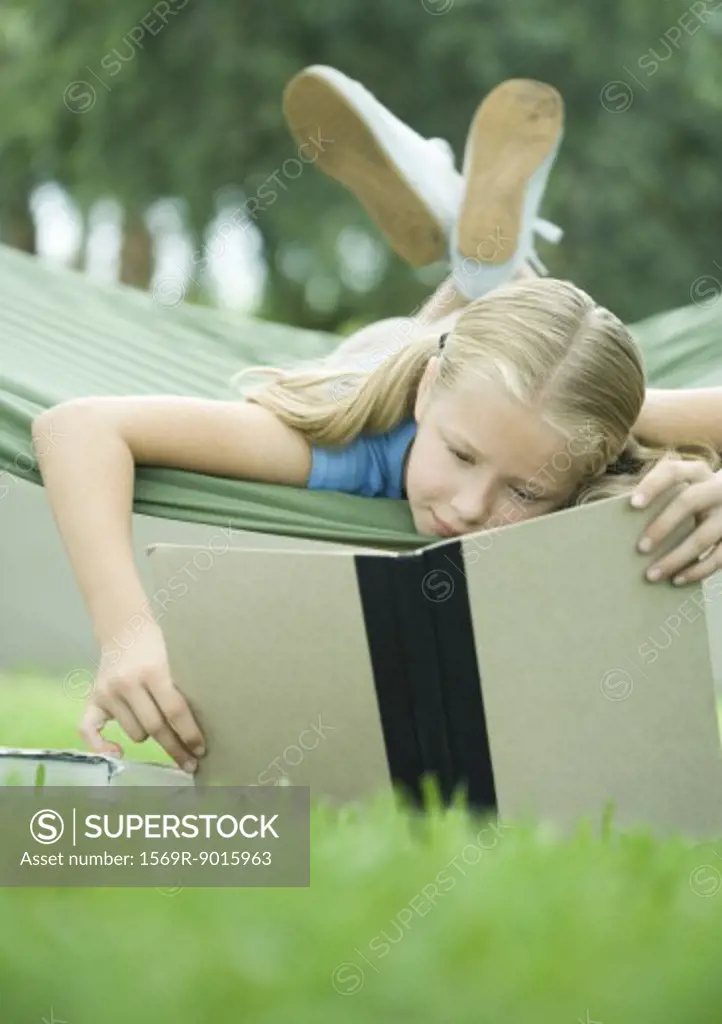 Girl lying in hammock reading book