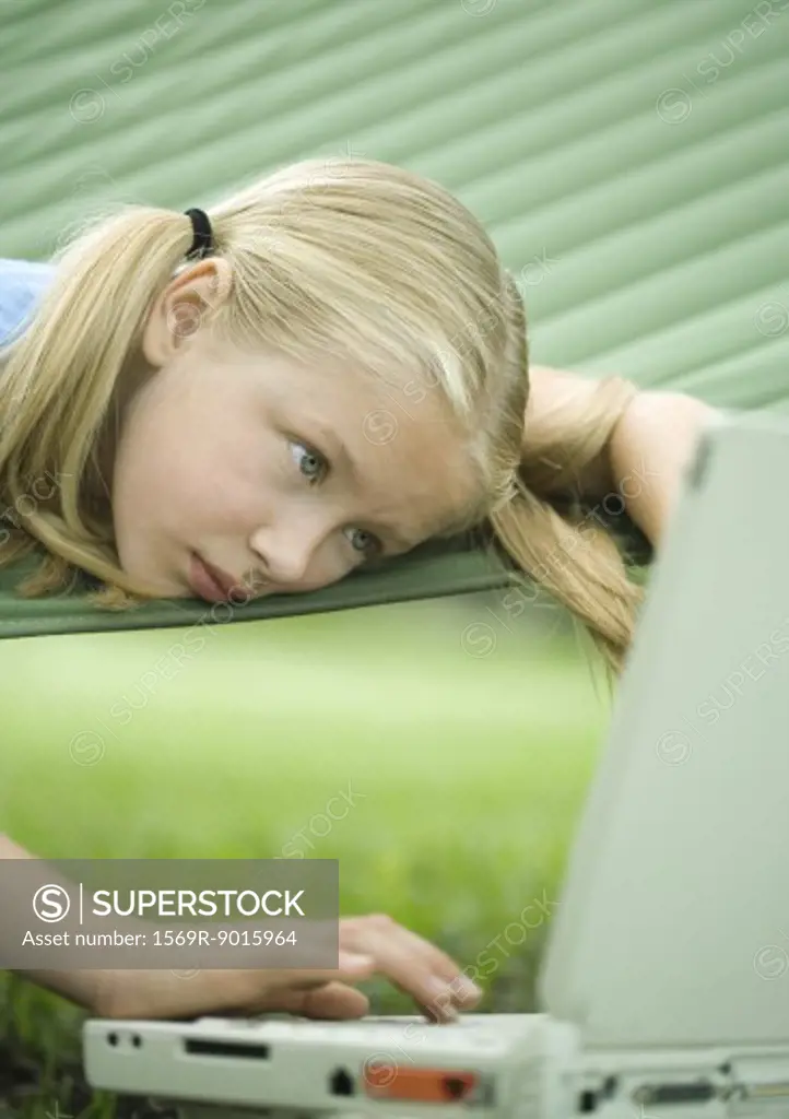 Girl lying in hammock using laptop