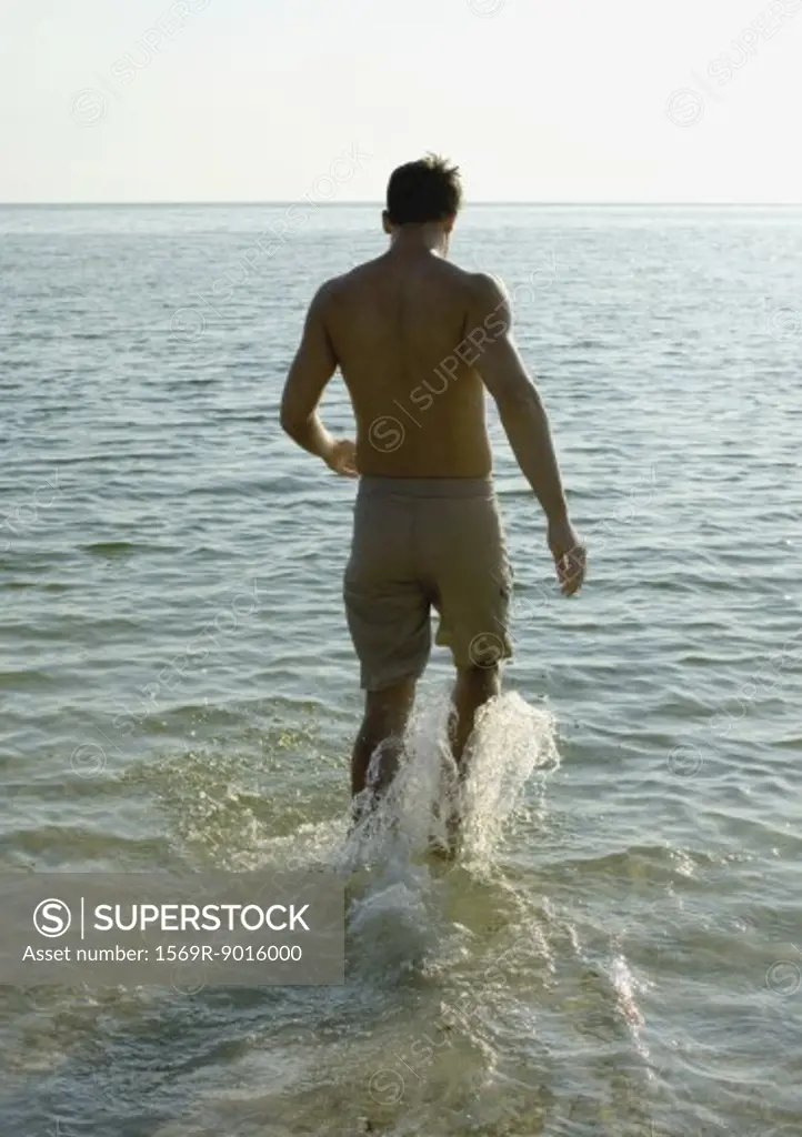 Man splashing in surf, rear view