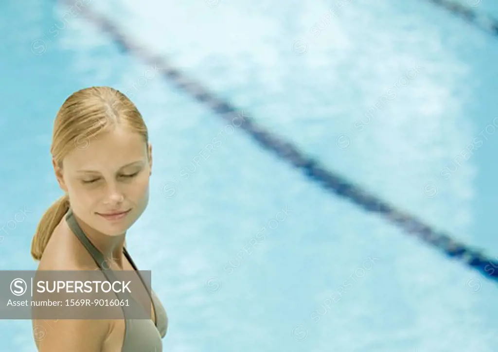 Woman near pool with eyes closed, smiling