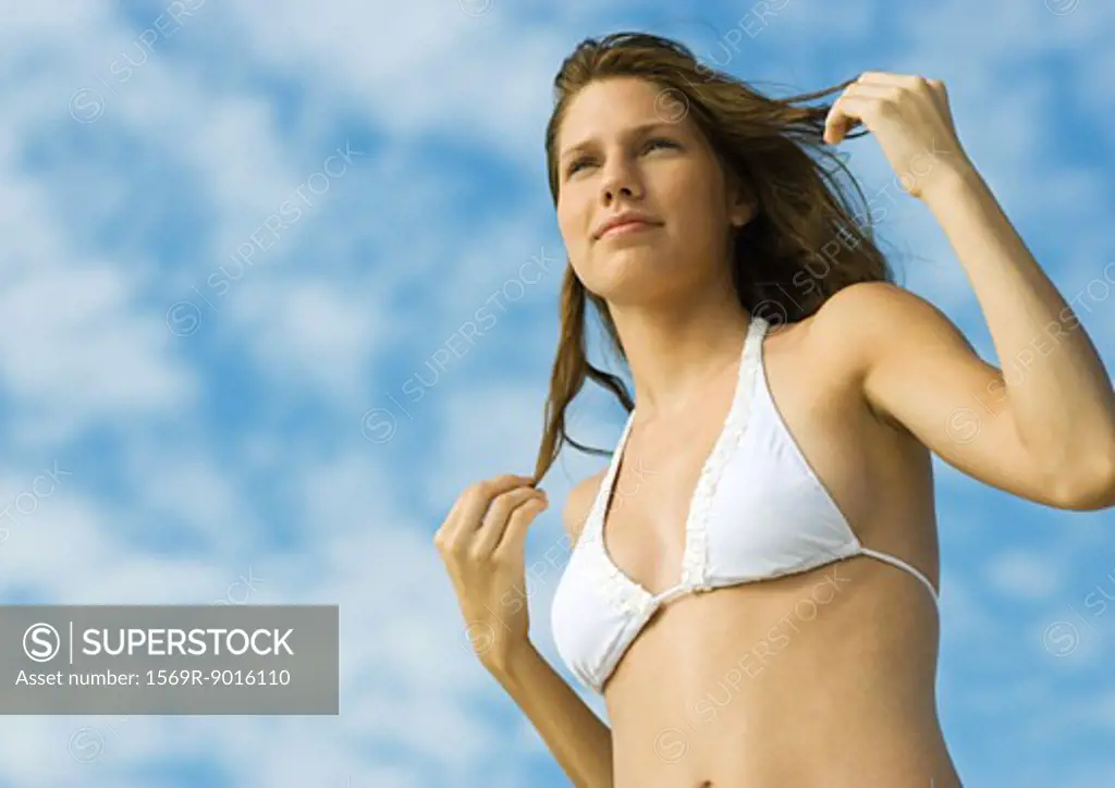 Woman in bikini standing with hands in hair, low angle view