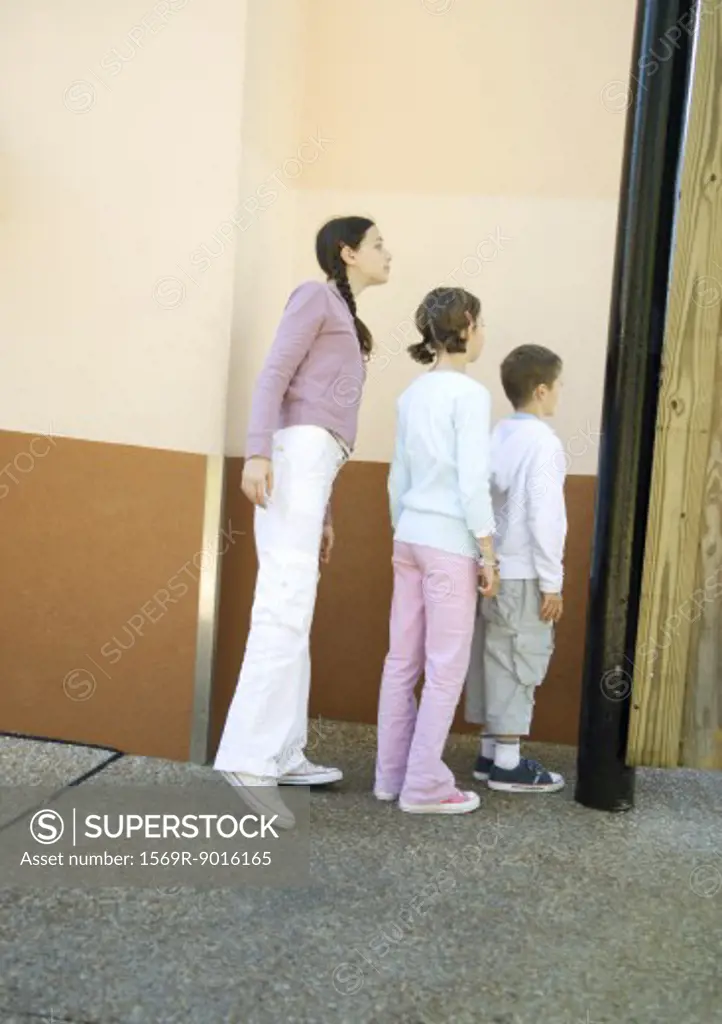 Line of children peeking around wall