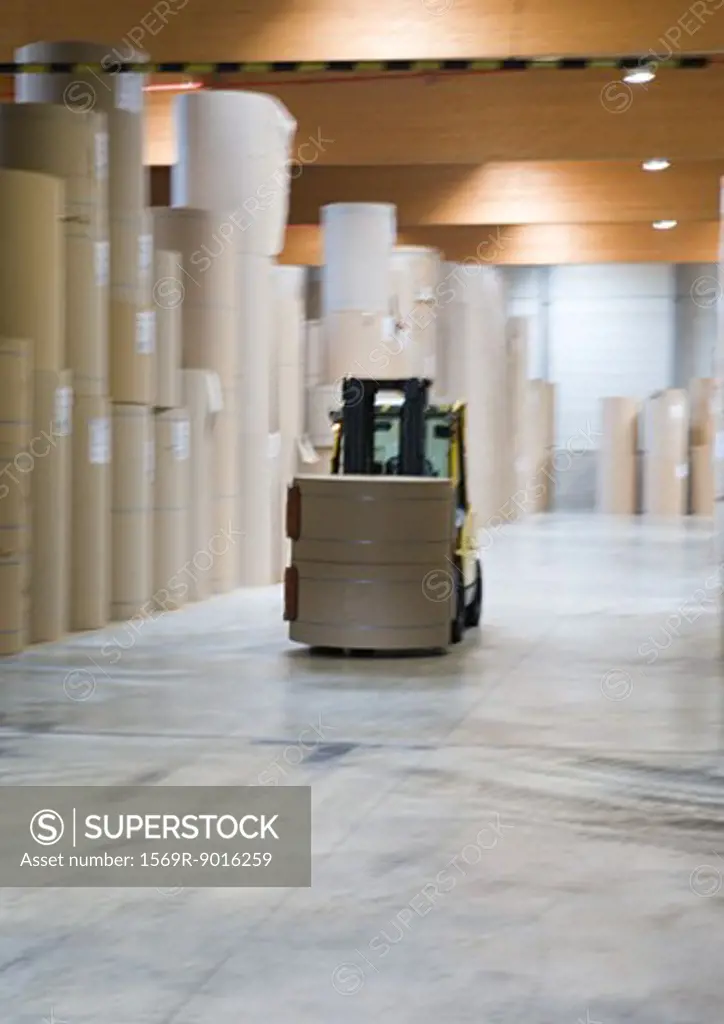 Forklift transporting roll of paper in warehouse