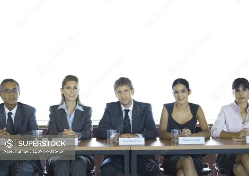 Executives sitting at conference table, looking at camera
