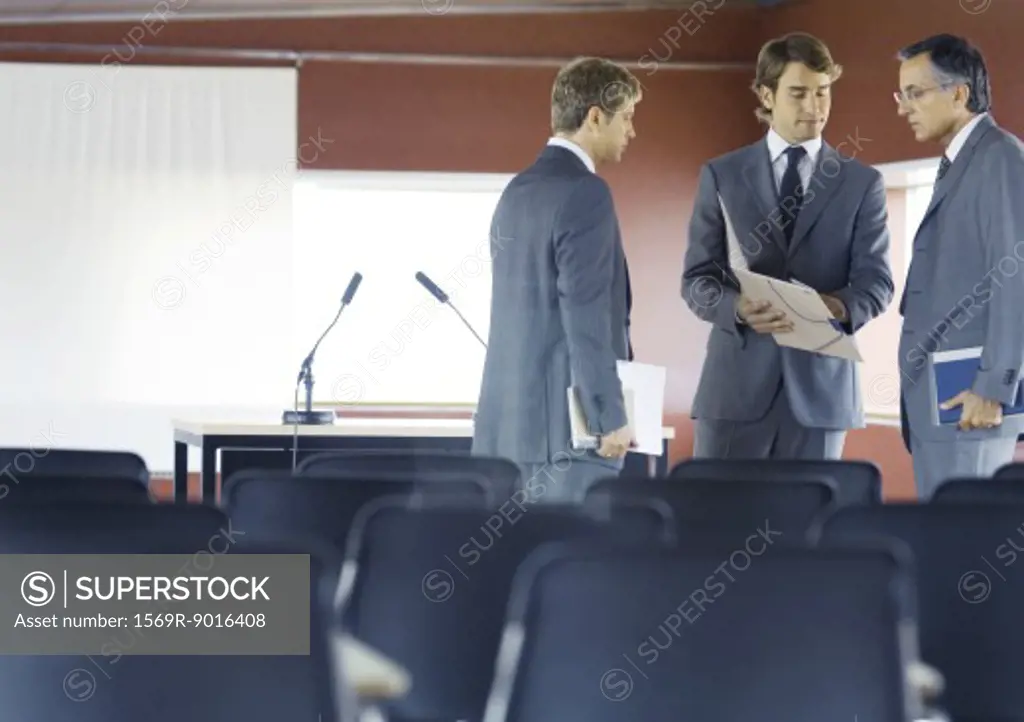 Executives standing, speaking in conference room