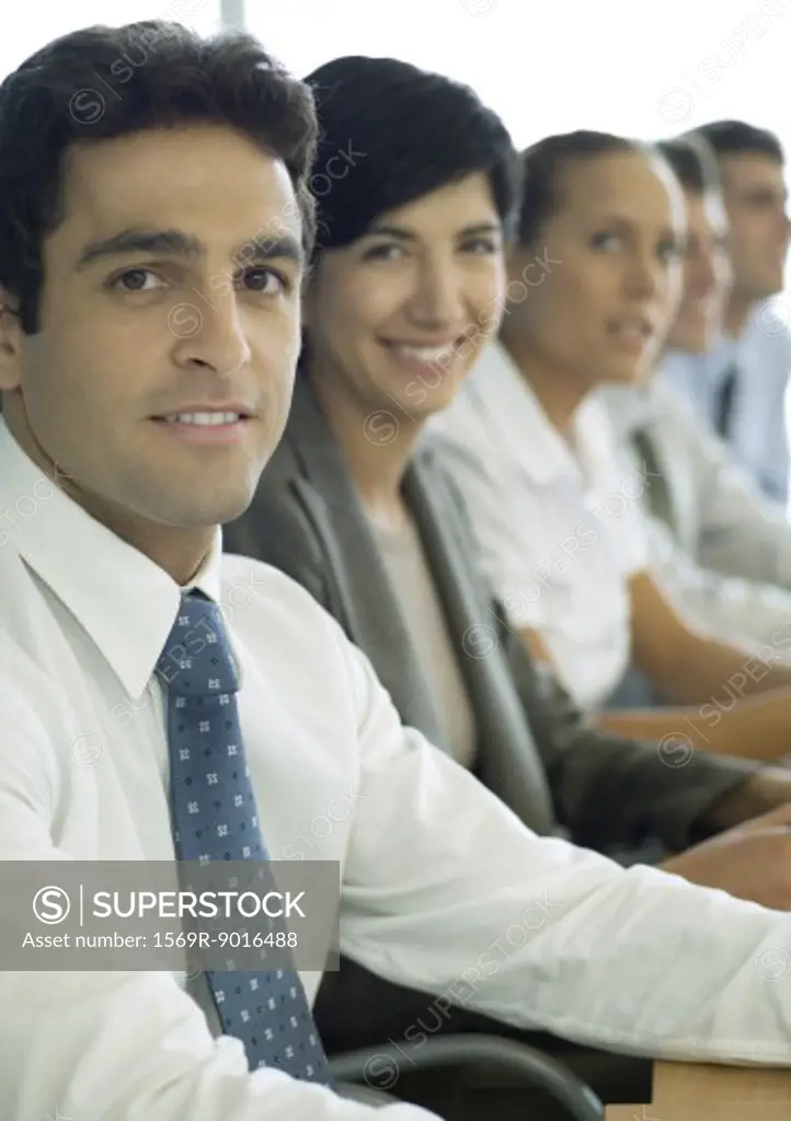Business associates sitting in row, focus on man in foreground