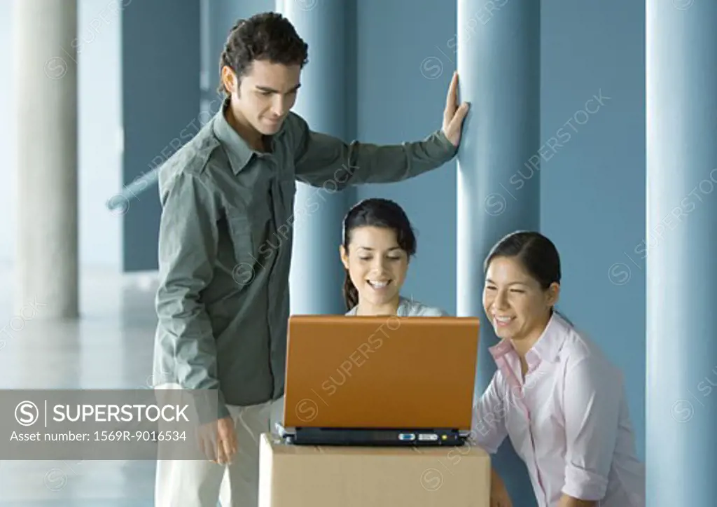 Businesspeople using laptop on cardboard box