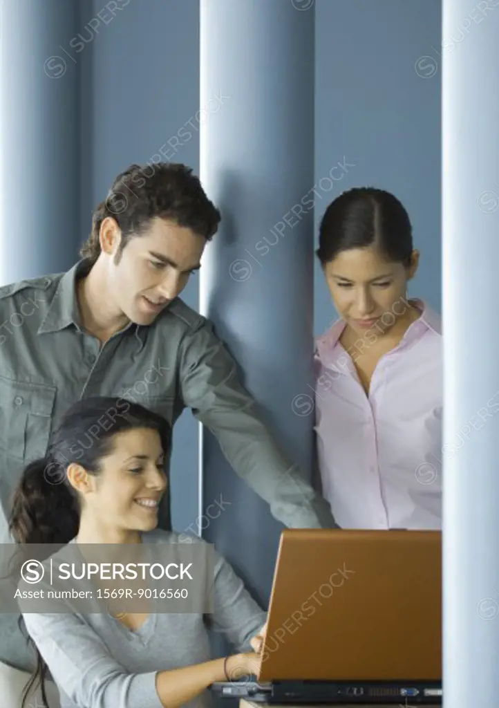 Three young adults using laptop computer together