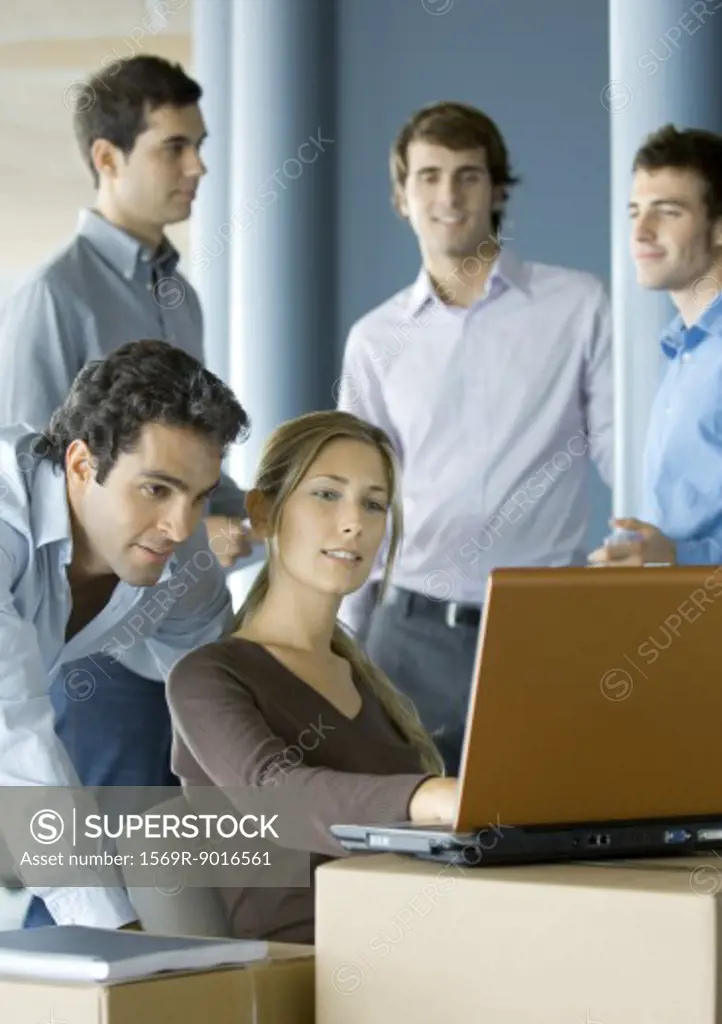 Business people using laptop on cardboard box