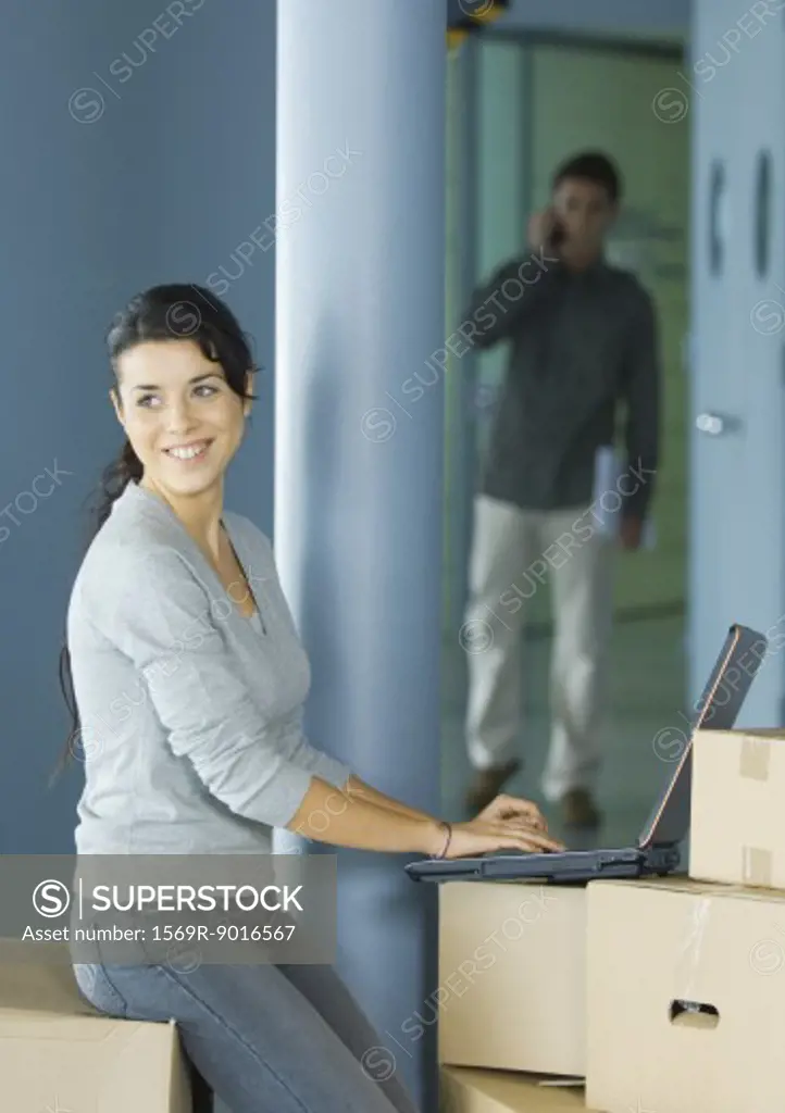 Young woman using laptop on cardboard box