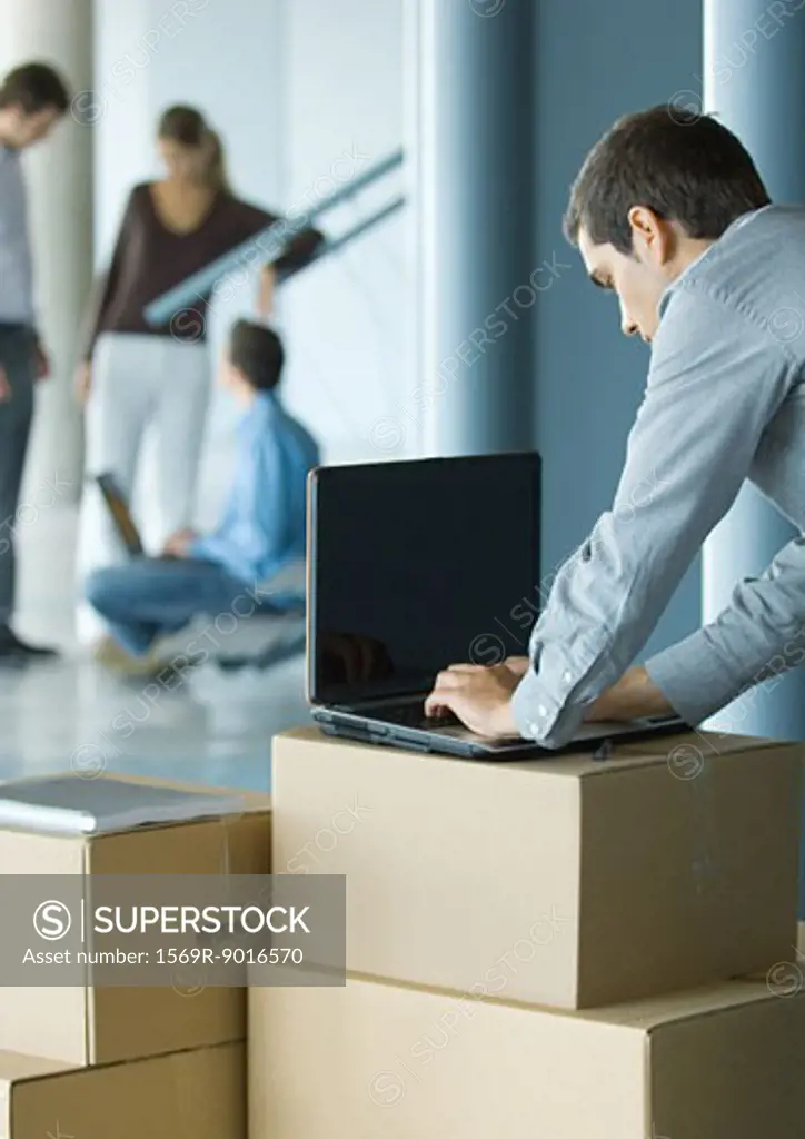 Businessman using laptop on cardboard box