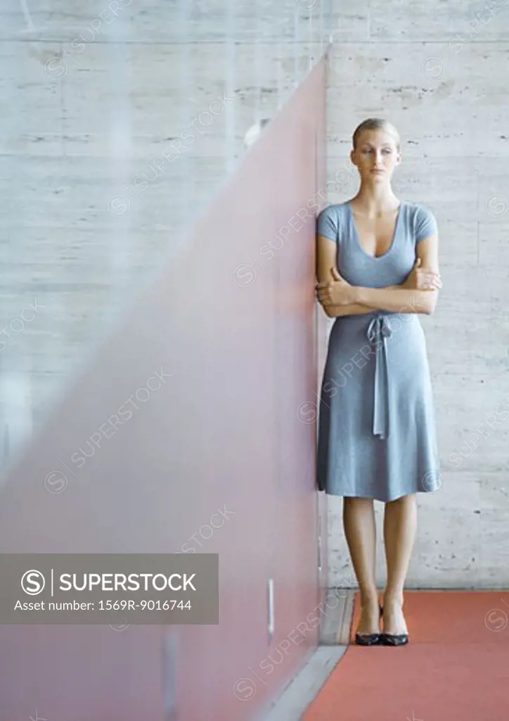 Woman standing, leaning against wall, full length portrait