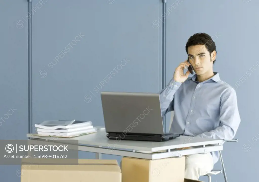 Man sitting at desk, using phone