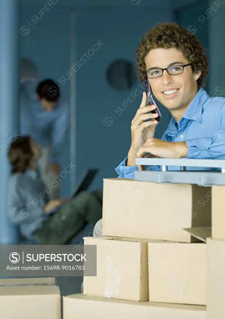 Young man using cell phone, cardboard boxes in foreground