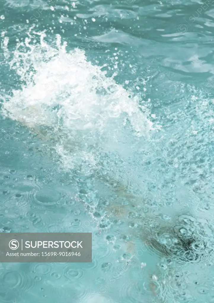 Surface of swimming pool splashing as swimmer moves underneath