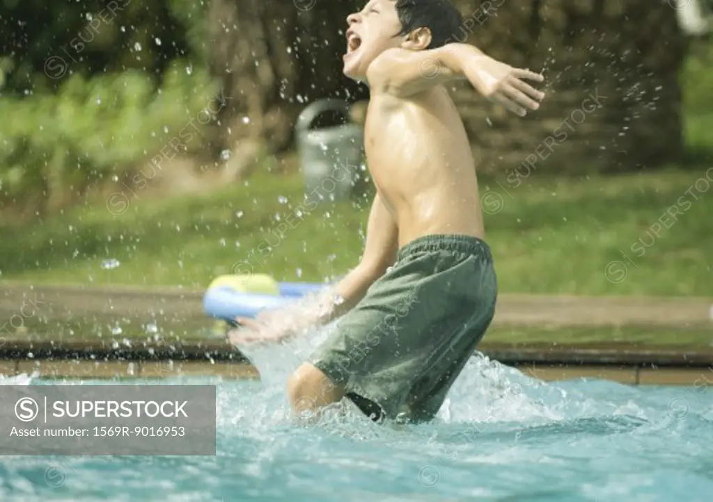 Boy splashing in swimming pool