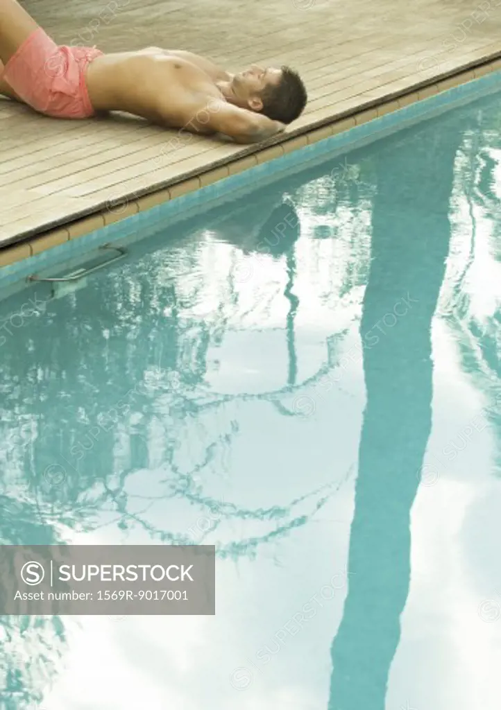 Man lying by edge of swimming pool