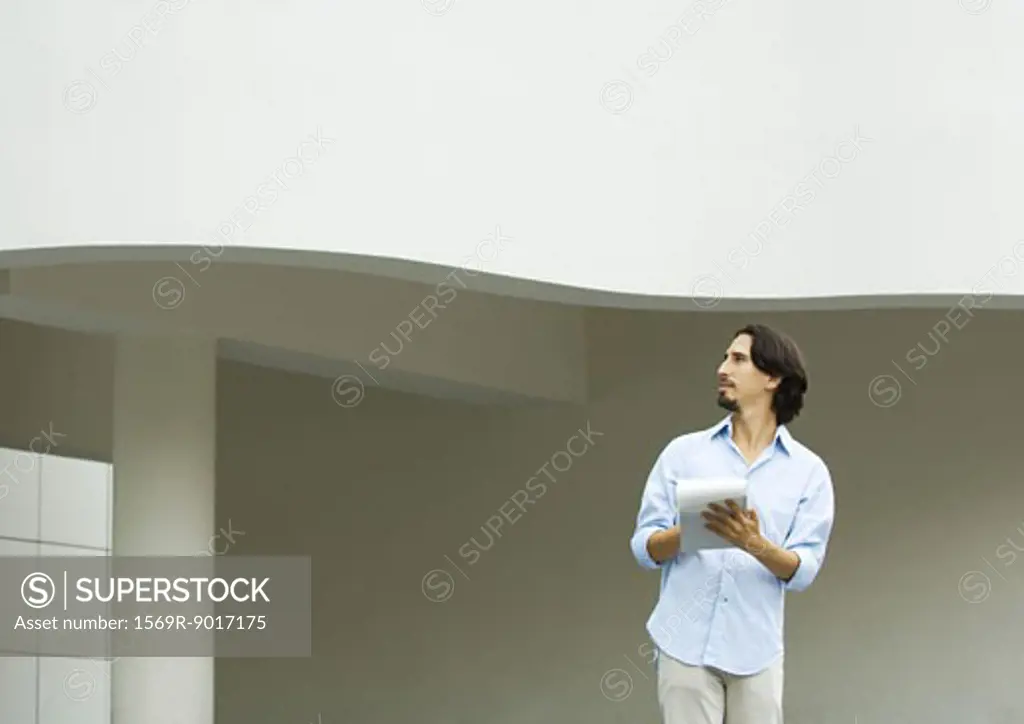 Man standing taking notes on pad of paper