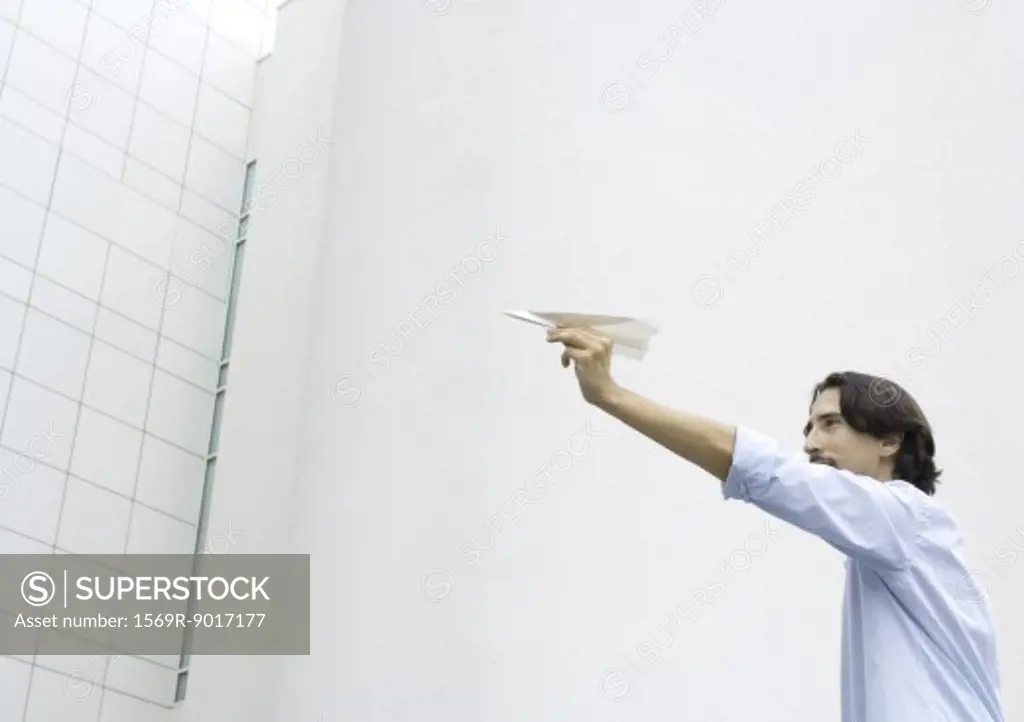 Man holding up paper airplane, low angle view