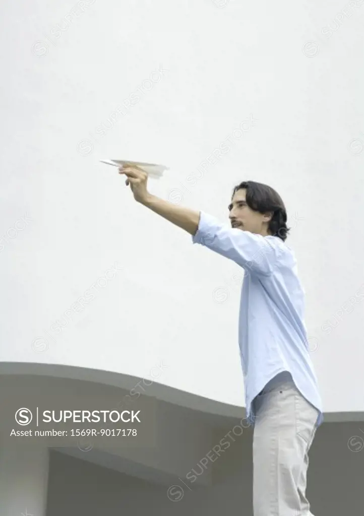 Man standing, aiming paper airplane