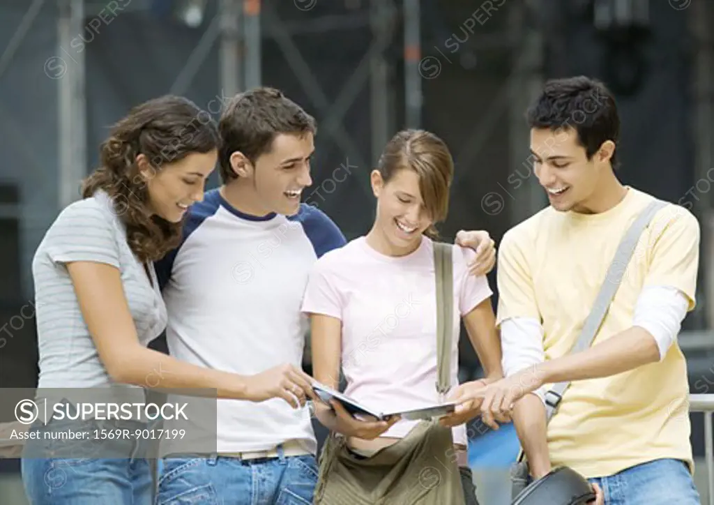 Teenagers standing together looking at notebook