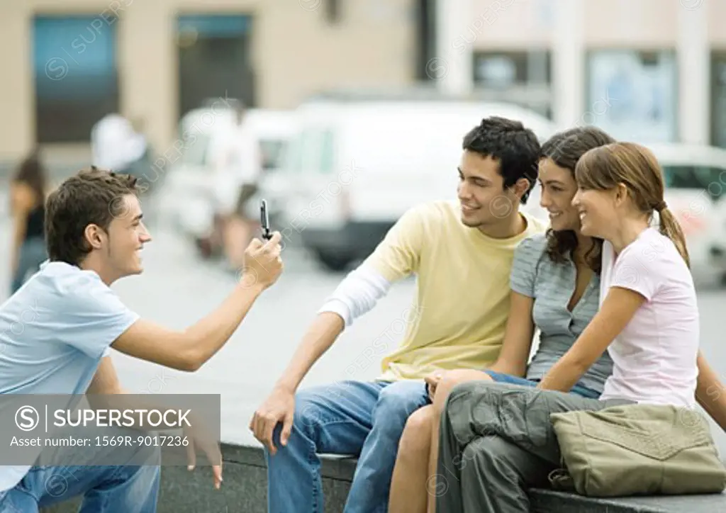 Teenage boy taking photo of friends with cell phone
