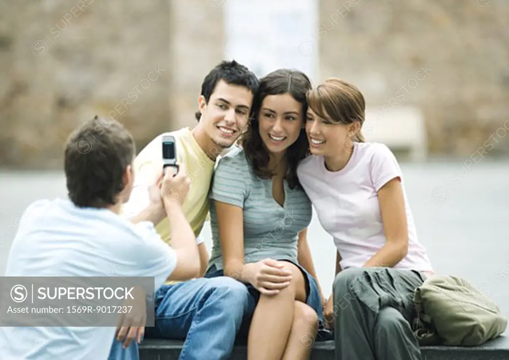 Teenage boy taking photo of friends with cell phone