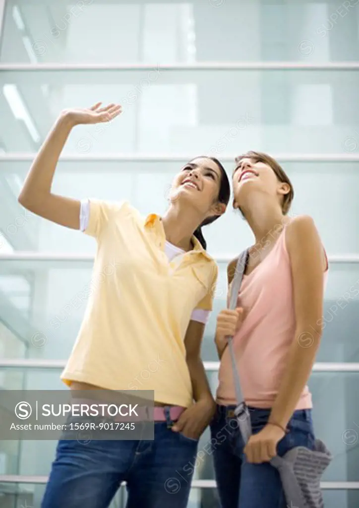 Two teenage girls looking up, one waving