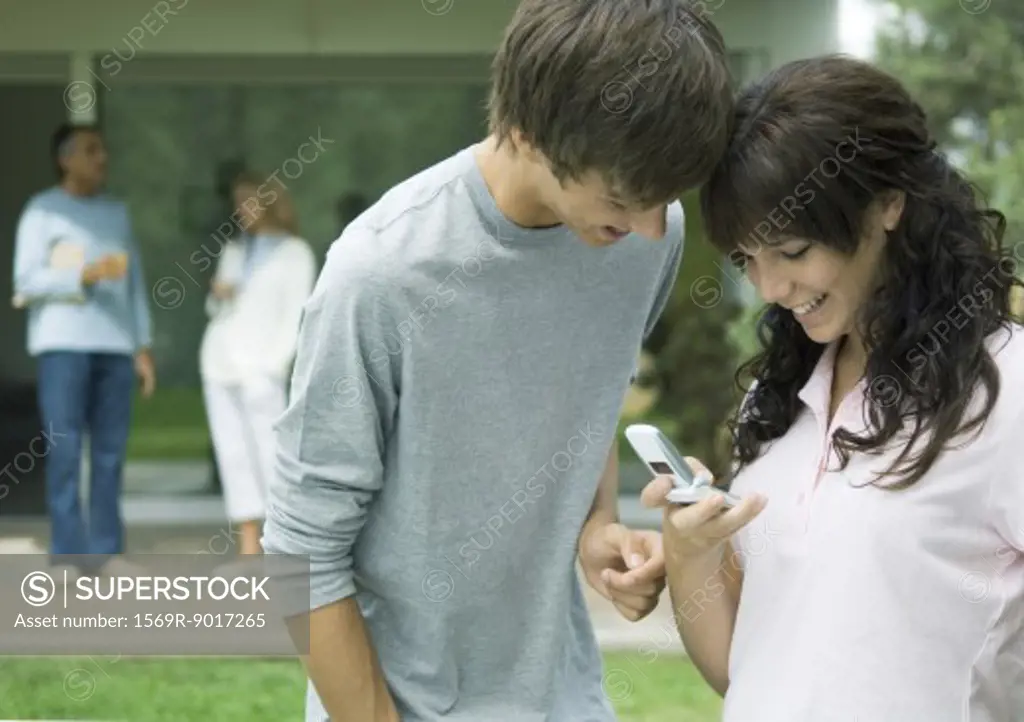 Teenage boy and girl looking at cell phone together