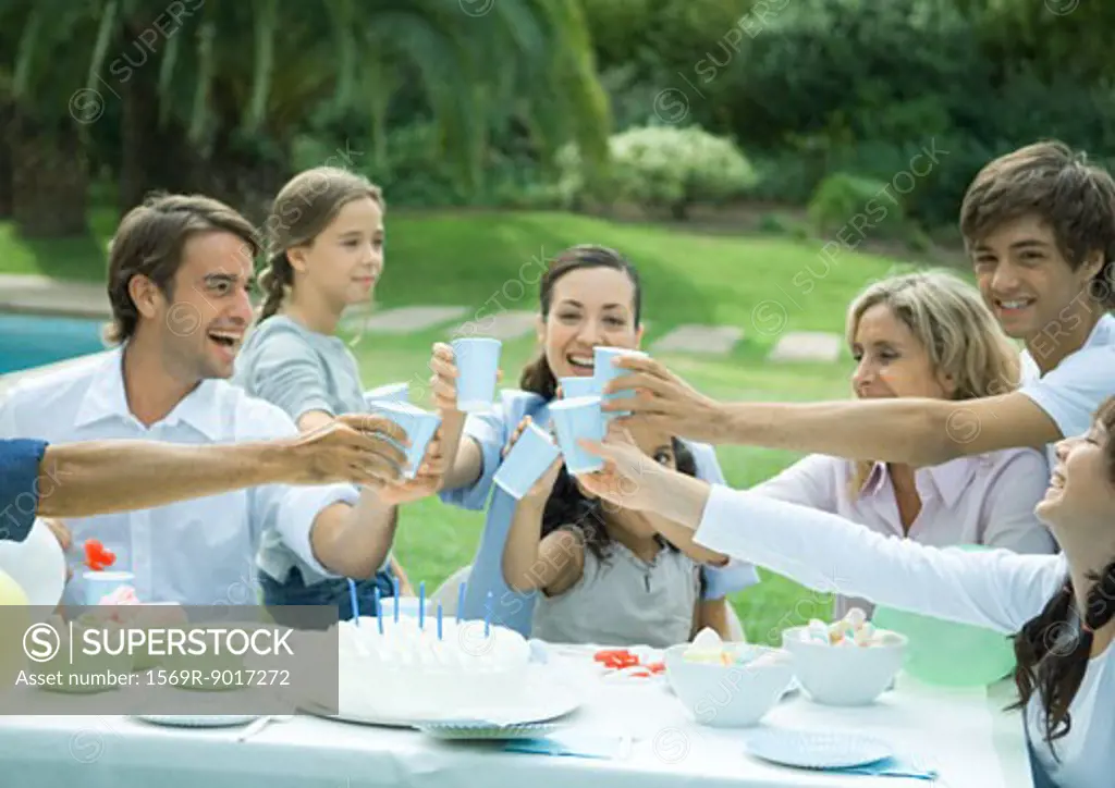 Family clinking cups over birthday cake