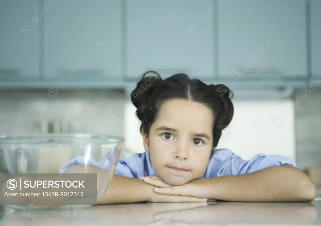 Girl resting head on counter next to bowl containing eggs