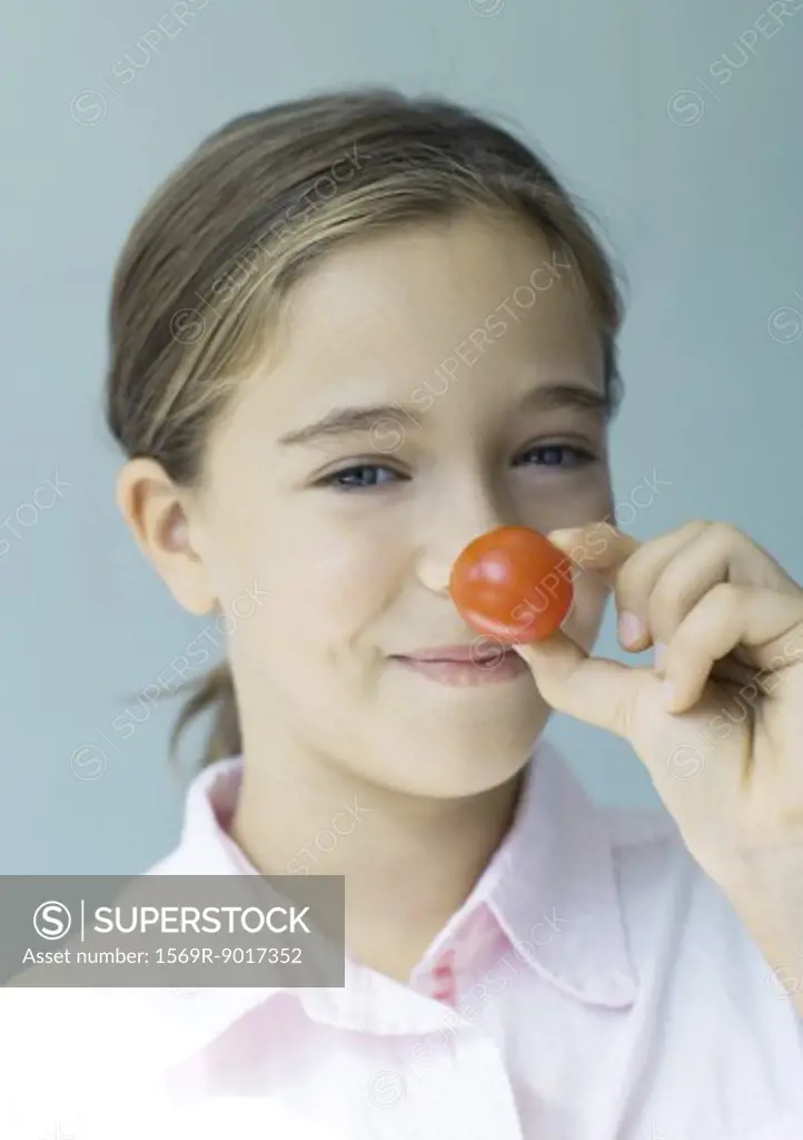 Girl holding up cherry tomato to nose