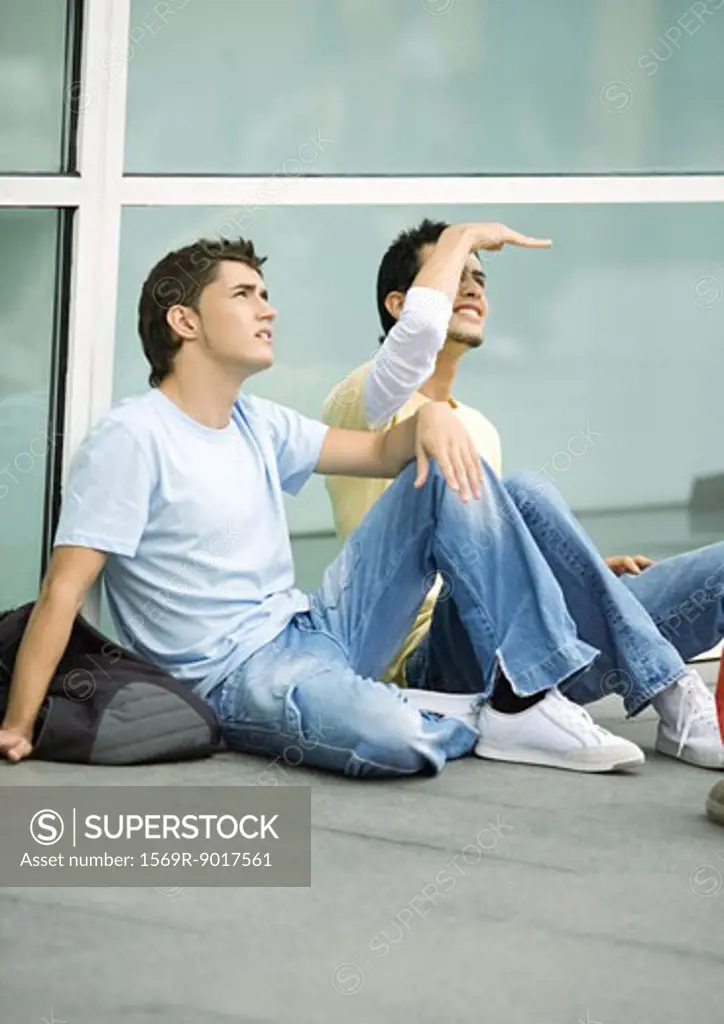Teen males sitting on ground, looking up