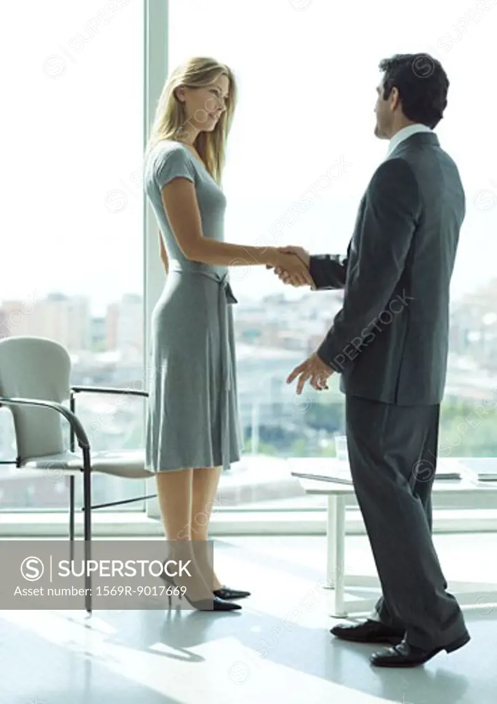 Businessman shaking hands with woman in lobby