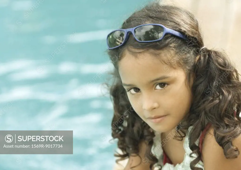 Girl with sunglasses on head, pool in background