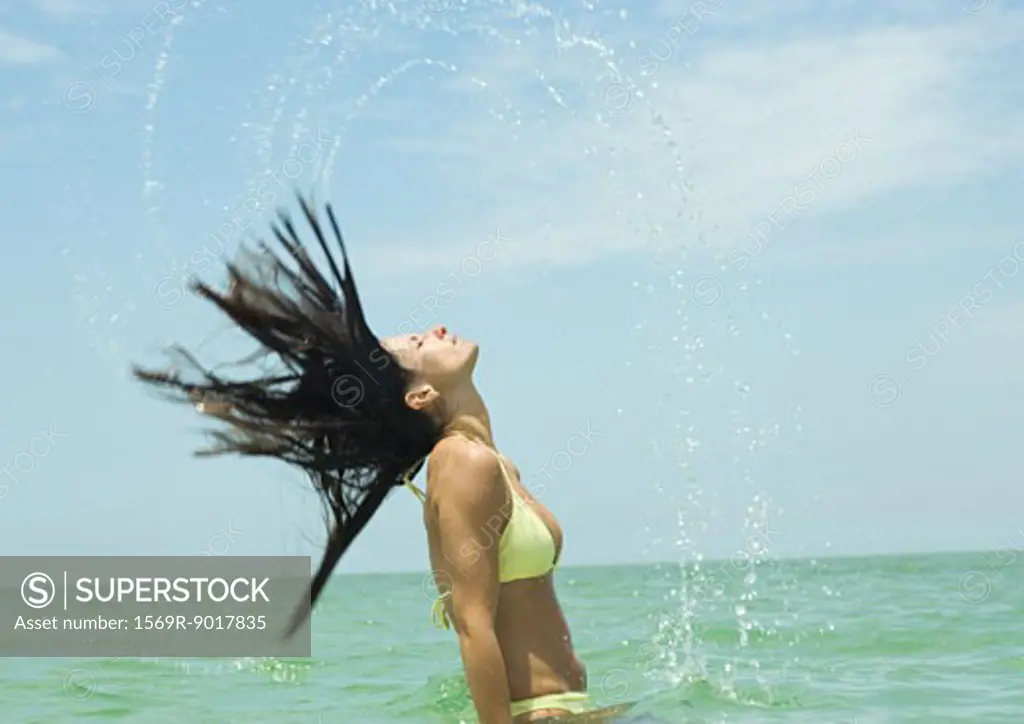 Woman standing in sea, flipping wet hair