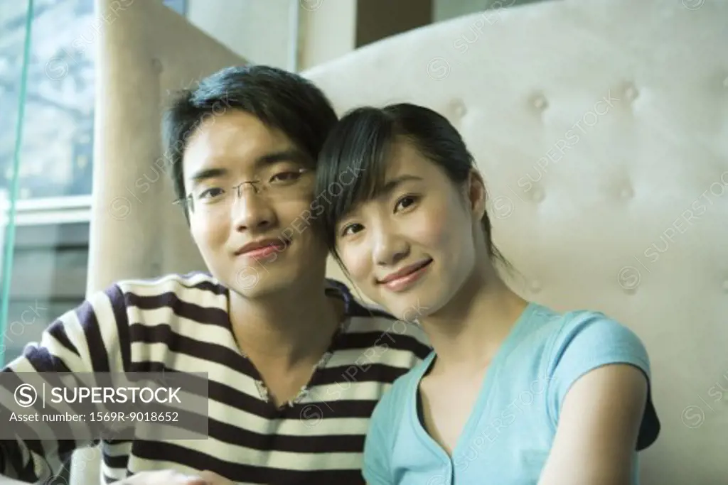 Young couple sitting in booth, smiling at camera