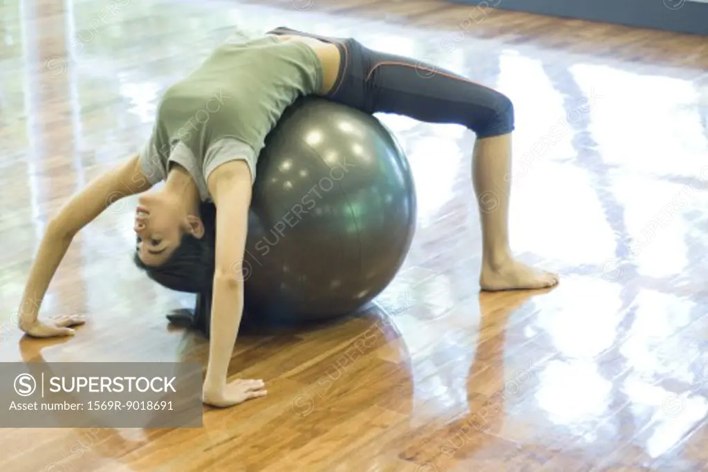 Young woman doing backbend on fitness ball